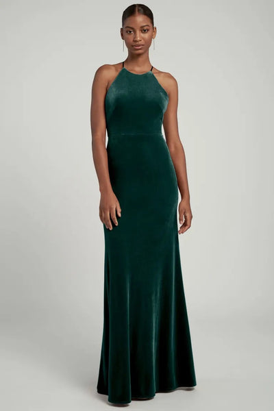 A woman standing in an elegant green Bailey bridesmaid dress by Jenny Yoo with a halter neckline from Bergamot Bridal.