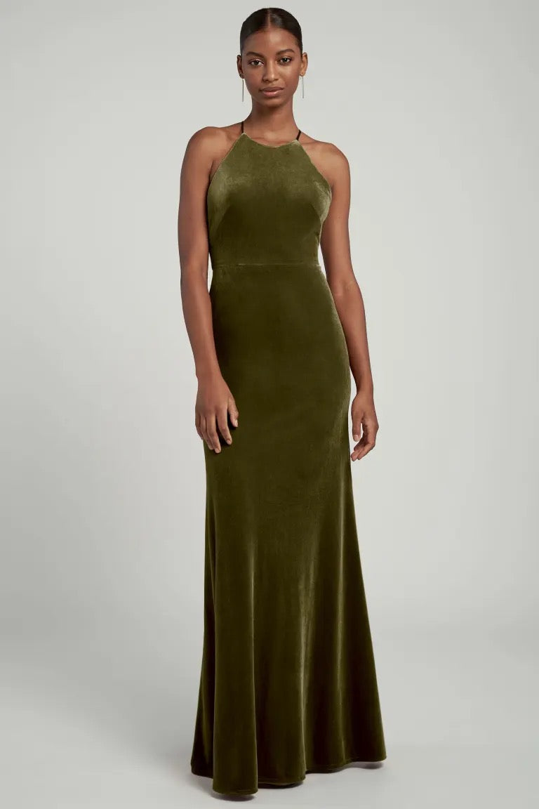 A woman in an elegant Bergamot Bridal Bailey velvet dress with a halter neckline, perfect for a bridal party.