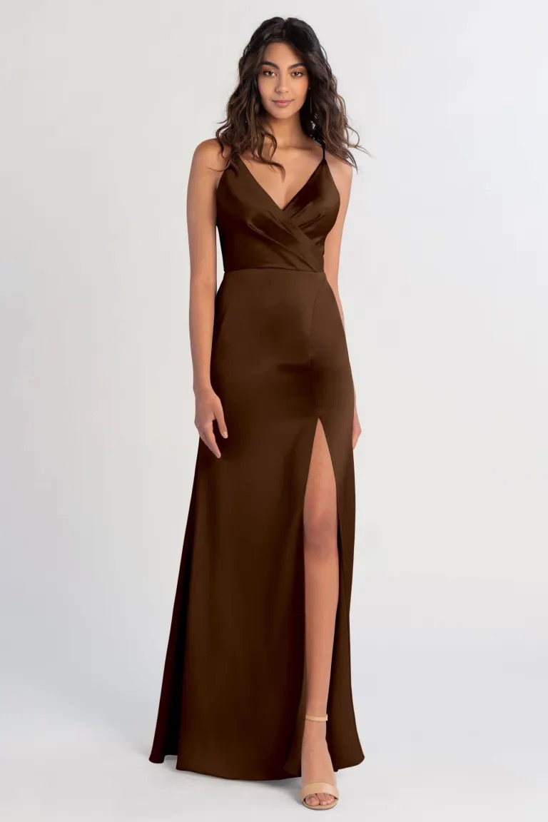 Woman in an elegant brown satin Beckette bridesmaid dress by Jenny Yoo with a high slit posing for a photograph at Bergamot Bridal.
