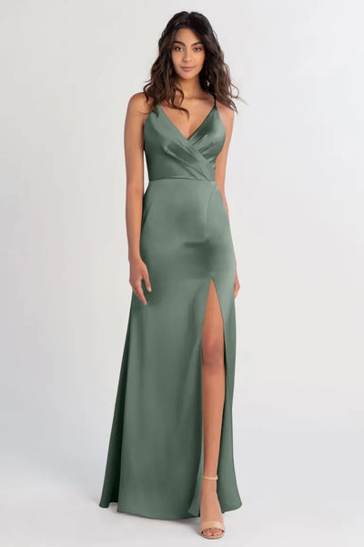 Woman posing in a green satin Beckette bridesmaid dress by Jenny Yoo with a thigh-high slit from Bergamot Bridal.