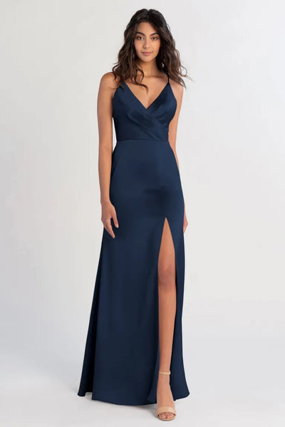 Woman posing in an elegant navy blue Beckette - Bridesmaid Dress by Jenny Yoo with a thigh-high slit, capturing the essence of old Hollywood glamour from Bergamot Bridal.