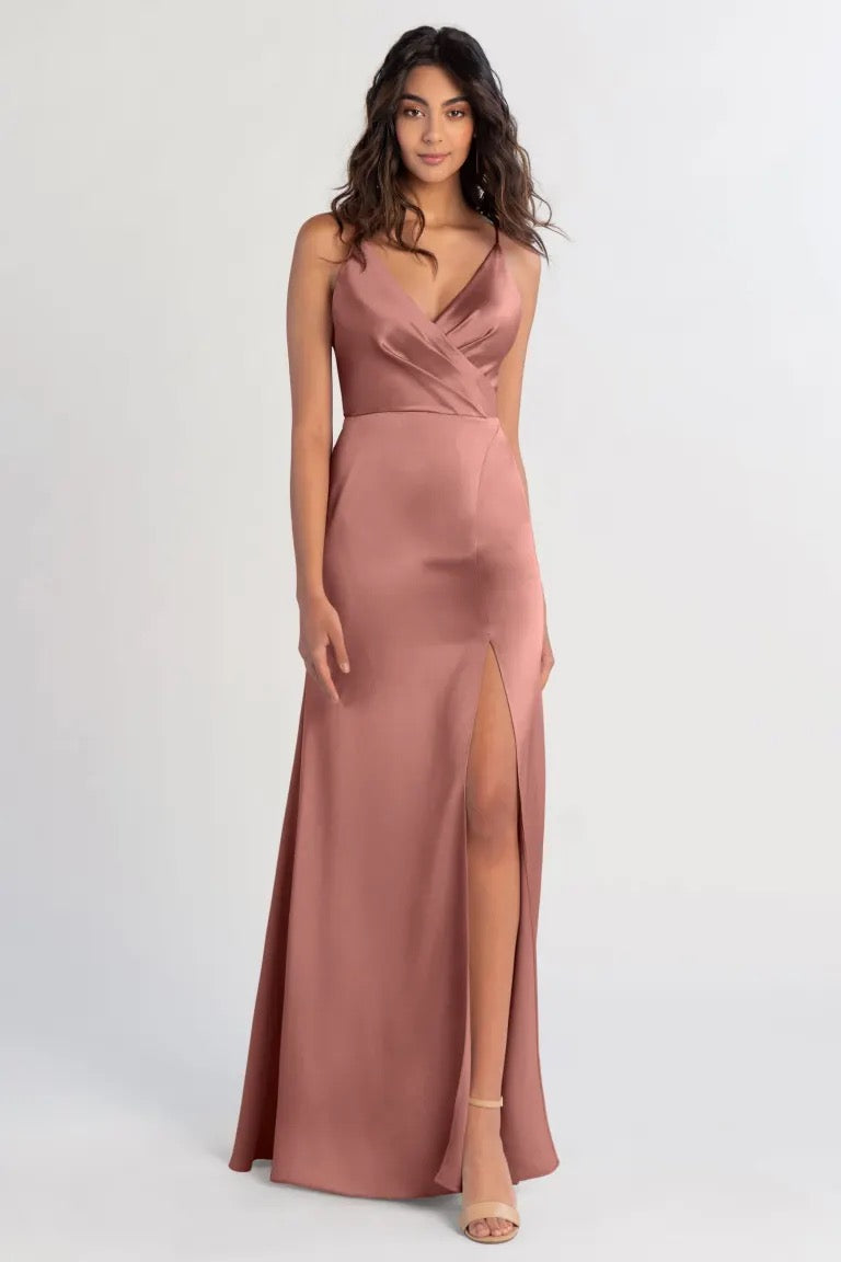 Woman modeling an elegant Beckette - Bridesmaid Dress by Jenny Yoo in dusky pink from Bergamot Bridal with a V-neck and a slit.
