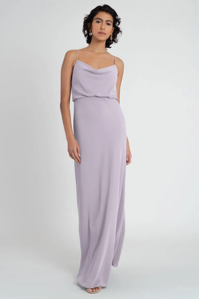 A woman standing in a studio setting, modeling a Jenny Yoo Bianca bridesmaid dress crafted from pebbled crepe fabric.