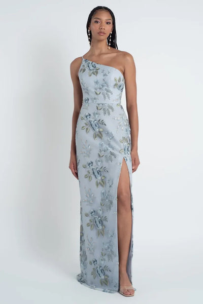 Woman in an enchanted Jenny Yoo Bridesmaid Dress featuring a floral embroidered tulle fabric and a thigh-high slit, standing against a white background.