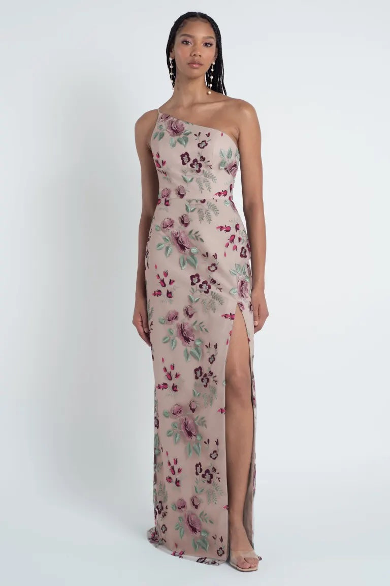 A woman in a Jenny Yoo Bridesmaid Dress with an Enchanted Floral embroidered tulle fabric stands against a plain background.