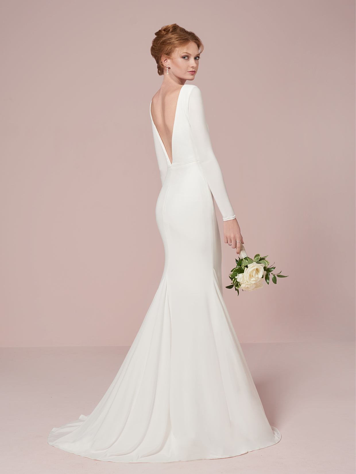 A woman in the Simple Long Sleeve Bridal Gown with Plunging Neckline by Christina Wu, from Bergamot Bridal, holds a bouquet of white flowers.