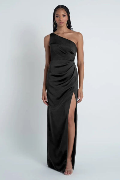 A woman posing in a Carolina - Jenny Yoo Bridesmaid Dress featuring a one-shoulder neckline and made from Luxe Faille fabric, with a high leg slit from Bergamot Bridal.