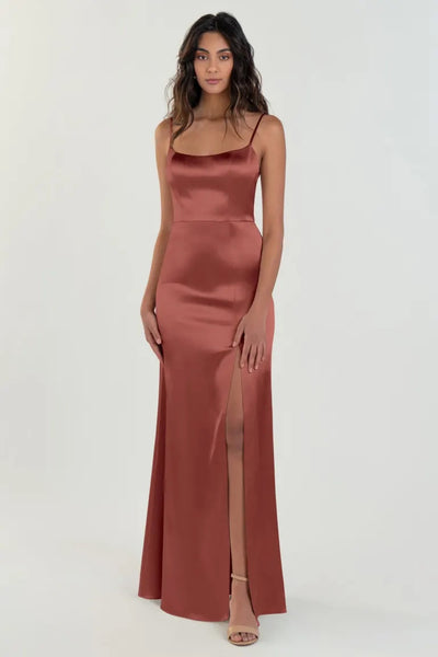 A woman in a sleek satin back crepe evening gown with a thigh-high slit and scoop neck - Chase Bridesmaid Dress by Jenny Yoo from Bergamot Bridal.