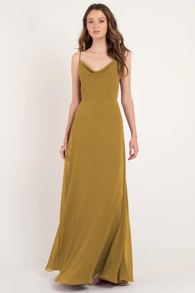 Woman in a long, olive green Colby - Jenny Yoo Bridesmaid Dress with a cowl neckline posing against a white background from Bergamot Bridal.