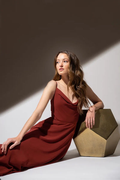 Woman in a Colby - Jenny Yoo Bridesmaid Dress sitting next to a geometric shape with dramatic lighting.