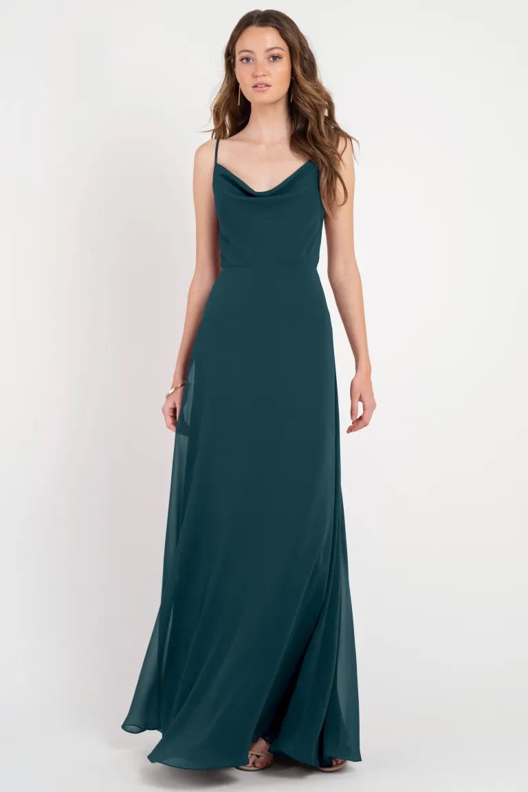 A woman modeling a long, teal Colby - Jenny Yoo Bridesmaid Dress with a cowl neckline from Bergamot Bridal.