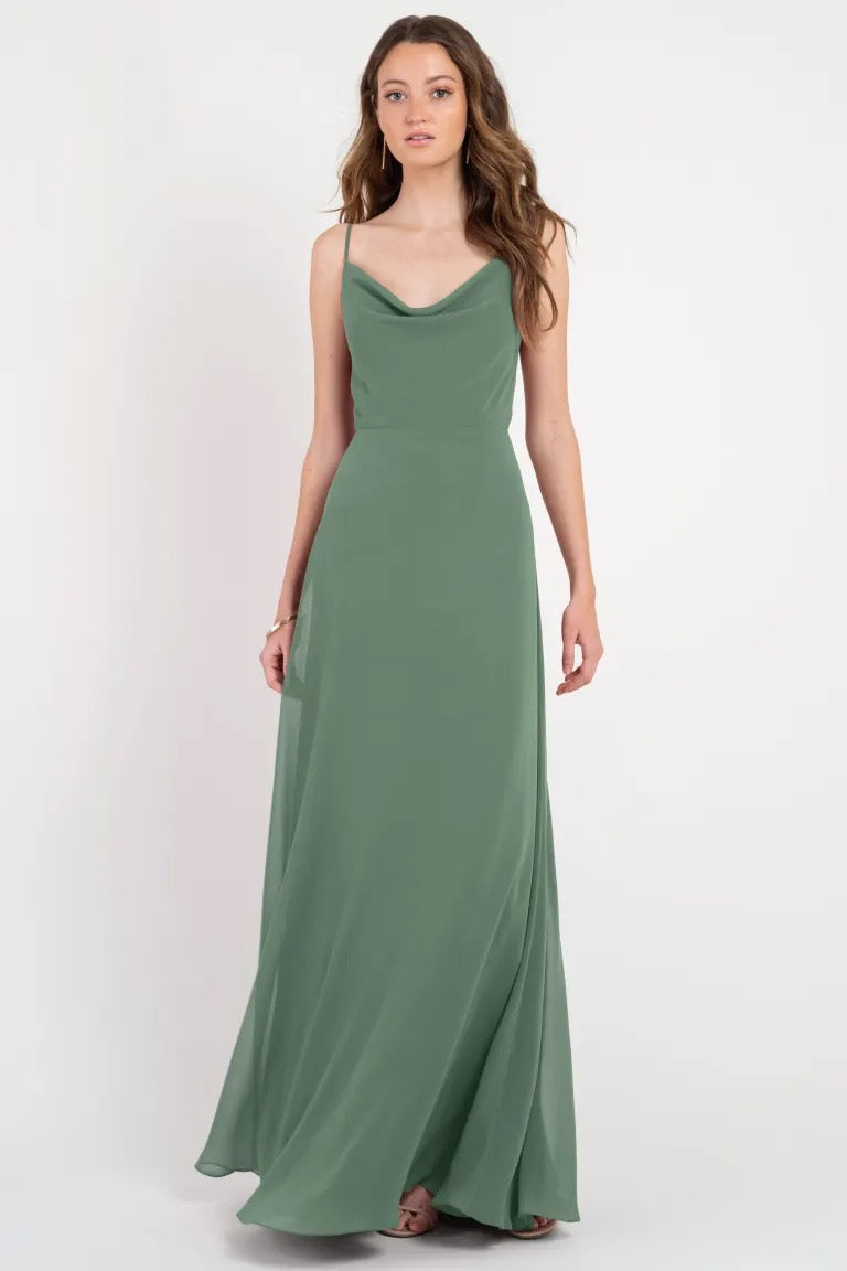A woman in an elegant green floor-length slip Colby - Jenny Yoo Bridesmaid Dress from Bergamot Bridal.