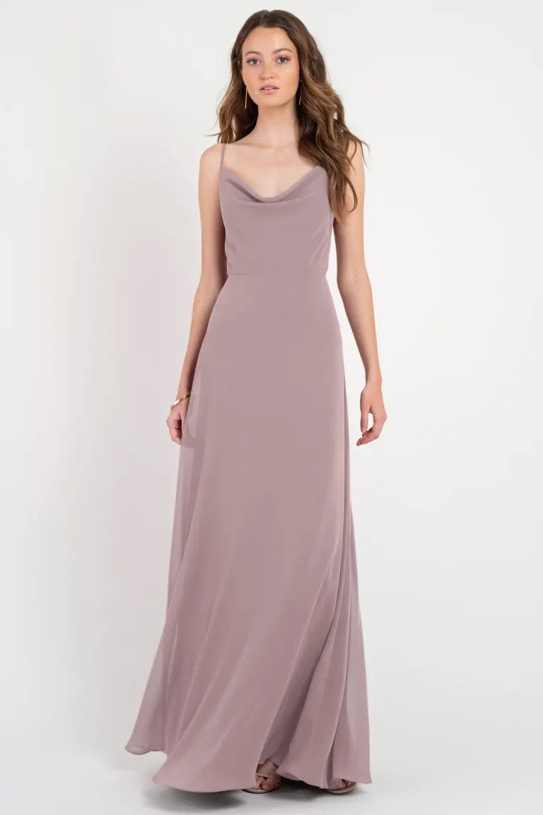 Woman posing in an elegant, floor-length mauve Colby - Jenny Yoo Bridesmaid Dress with a cowl neckline from Bergamot Bridal.
