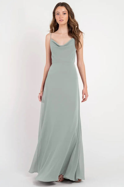 Woman wearing a long, flowing sage green Colby - Jenny Yoo Bridesmaid Dress with a cowl neckline by Bergamot Bridal.