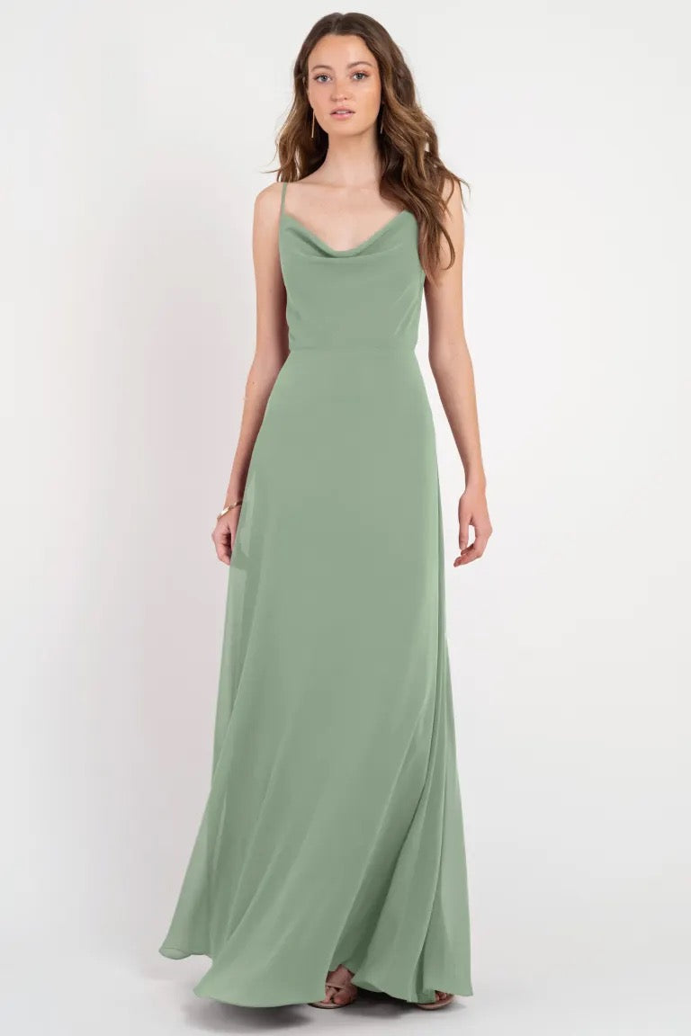 Woman posing in an elegant sage green slip dress with a cowl neckline - Colby by Jenny Yoo bridesmaid dress from Bergamot Bridal.