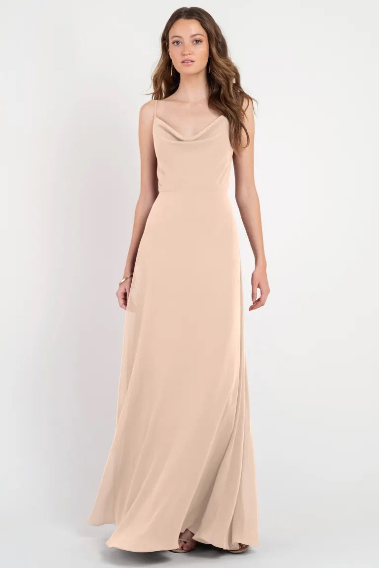 Woman posing in a formal beige Colby - Jenny Yoo Bridesmaid Dress with a twirl-worthy skirt against a neutral background from Bergamot Bridal.