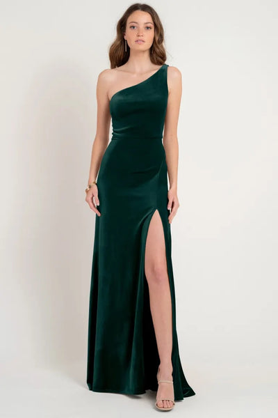 Woman in an elegant one-shoulder sleek dress crafted from Stretch Velvet with a thigh-high slit, wearing the Cybill Bridesmaid Dress by Jenny Yoo from Bergamot Bridal.