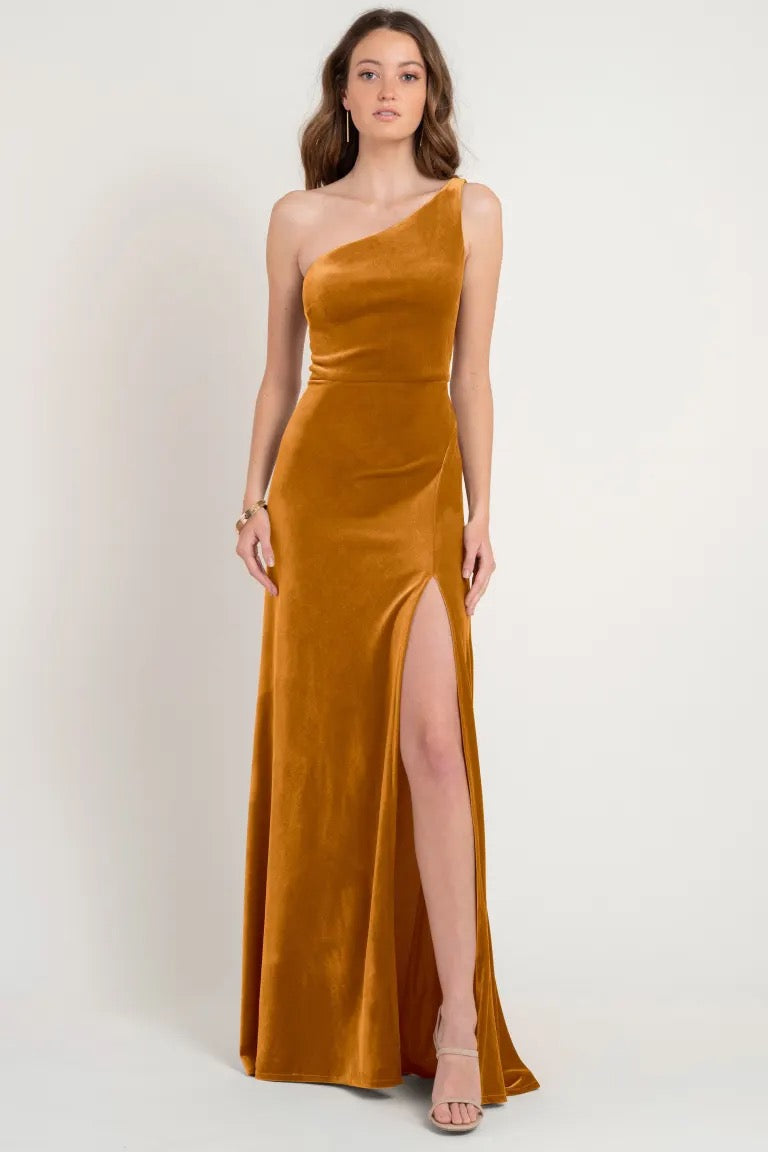 Woman in an elegant one-shoulder stretch velvet golden Cybill - Bridesmaid Dress by Jenny Yoo with a thigh-high slit, store sample size 12.