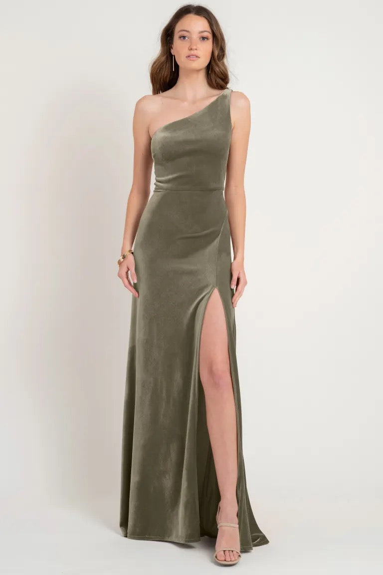 Woman in a one-shoulder olive green stretch velvet evening gown with a thigh-high slit, originally a store sample of the Cybill Bridesmaid Dress by Jenny Yoo from Bergamot Bridal.