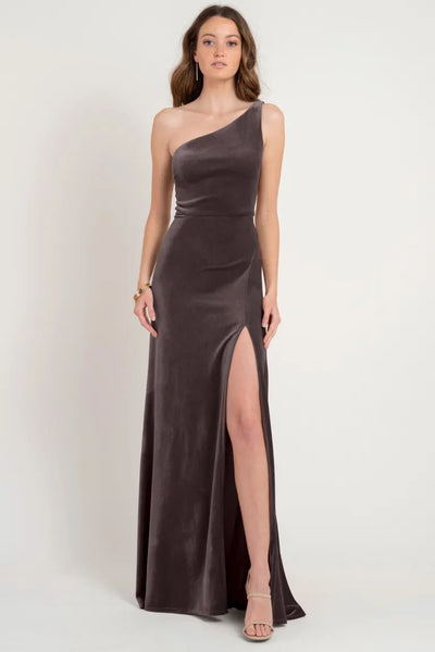 Woman posing in an elegant Cybill - Bridesmaid Dress by Jenny Yoo from Bergamot Bridal, a one-shoulder stretch velvet gown with a thigh-high slit, sample size 12.