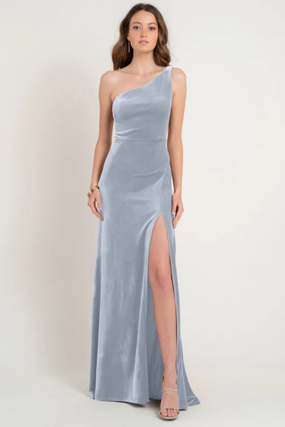 A woman modeling a store sample size 12, one-shoulder, silver evening gown crafted from Stretch Velvet with a thigh-high slit. The Cybill bridesmaid dress by Jenny Yoo at Bergamot Bridal.
