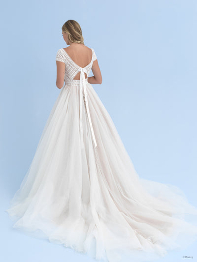Woman in an elegant Bergamot Bridal Allure Disney Wedding Dress - Rapunzel - Off The Rack with lace bodice detailing and a flowing train against a blue background.