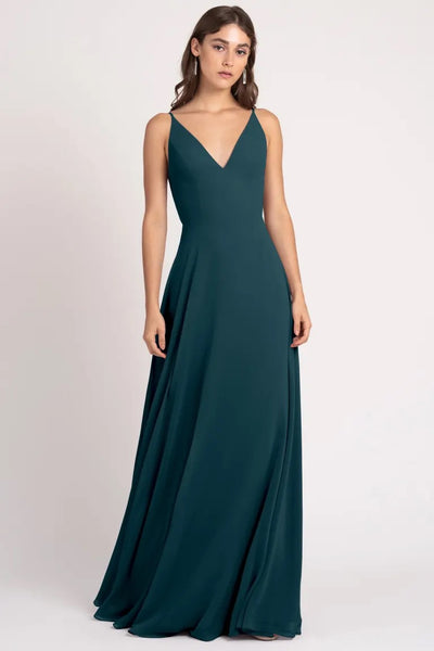 A woman in an elegant teal evening gown with a-line silhouette and a v-neckline, wearing the Dani Bridesmaid Dress by Jenny Yoo from Bergamot Bridal.