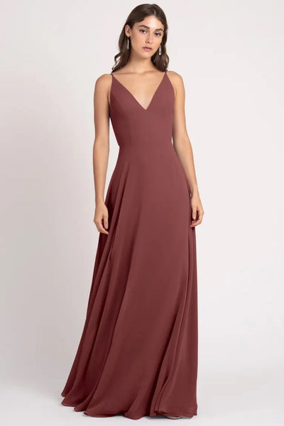 Woman posing in an elegant sleeveless burgundy Dani Bridesmaid Dress by Jenny Yoo with sharp tailoring and a v-neckline from Bergamot Bridal.