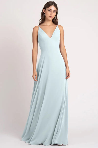 Woman in light blue evening gown with v-neckline and keyhole back, such as the Dani Bridesmaid Dress by Jenny Yoo at Bergamot Bridal.
