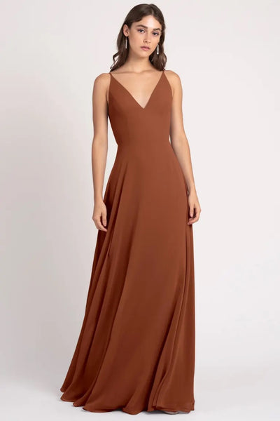Woman in a long brown evening dress with a v-neckline and keyhole back, wearing the Dani Bridesmaid Dress by Jenny Yoo from Bergamot Bridal.