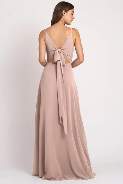 A woman wearing an elegant backless Dani - Bridesmaid Dress by Jenny Yoo with a bow detail and sharp tailoring from Bergamot Bridal.