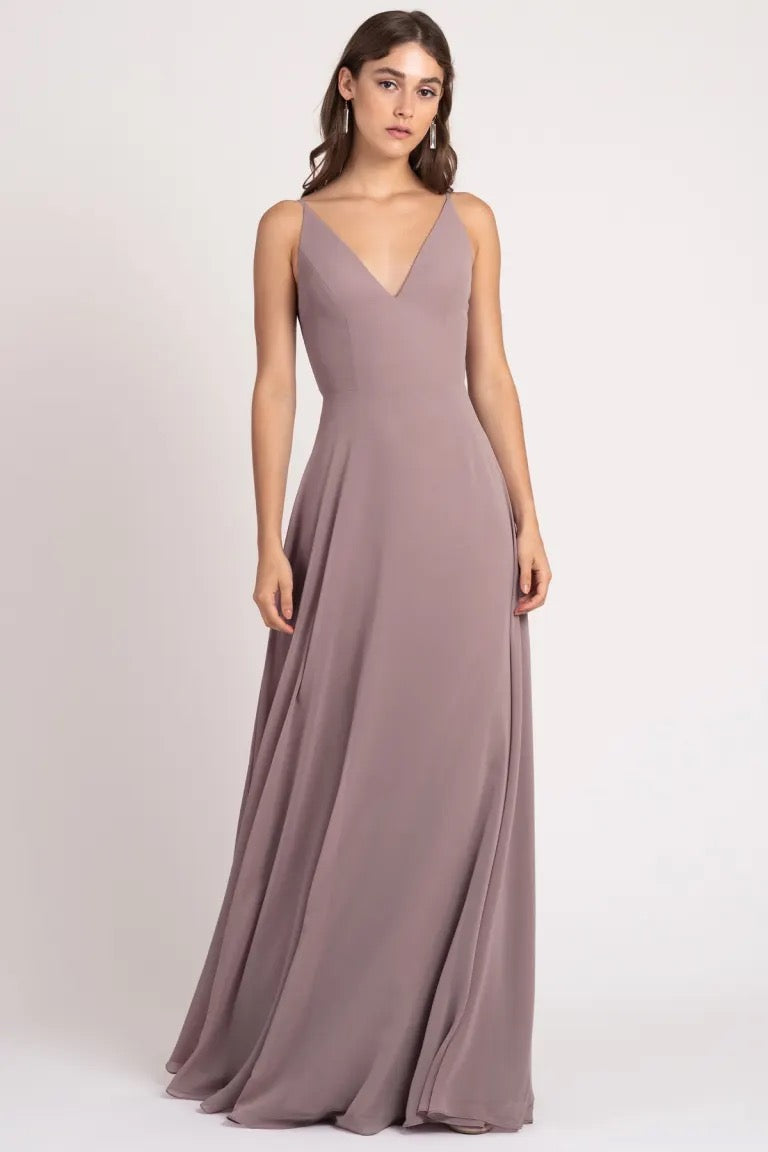 Woman wearing a sleeveless, a-line silhouette, v-neck, floor-length taupe Dani bridesmaid dress by Jenny Yoo with sharp tailoring from Bergamot Bridal.