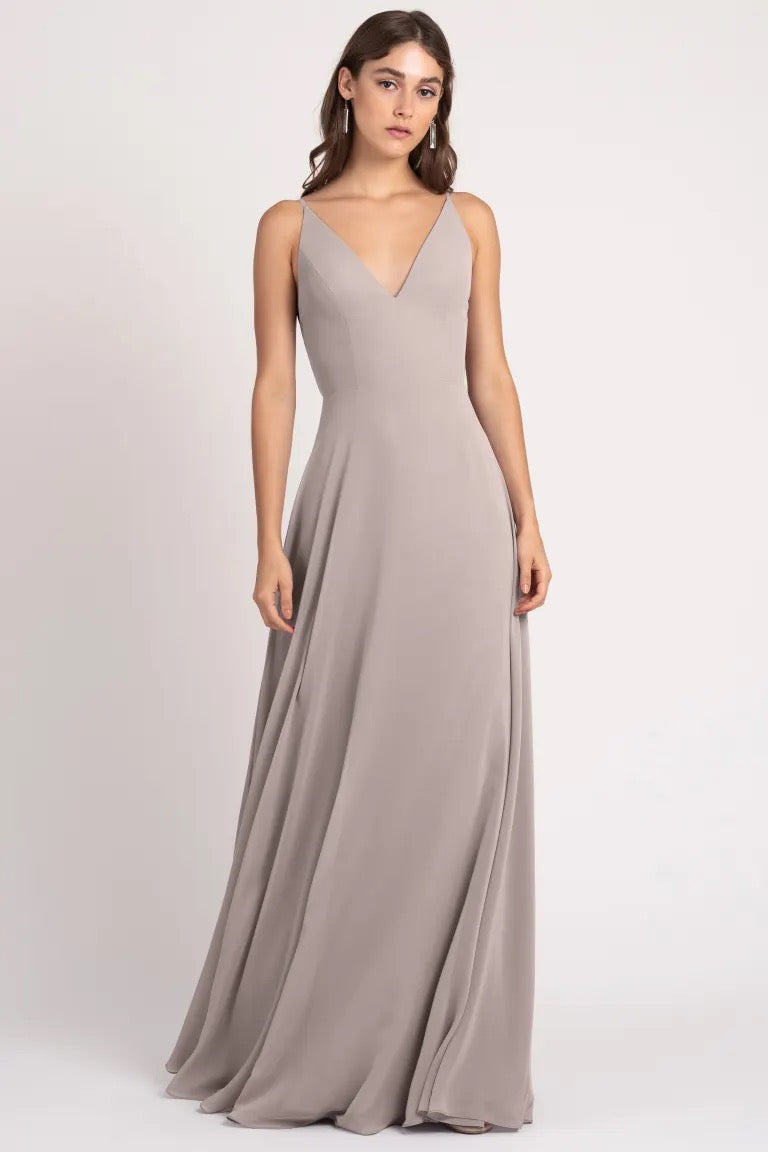 Woman posing in an elegant taupe Dani - Bridesmaid Dress by Jenny Yoo with a v-neckline and a keyhole back from Bergamot Bridal.