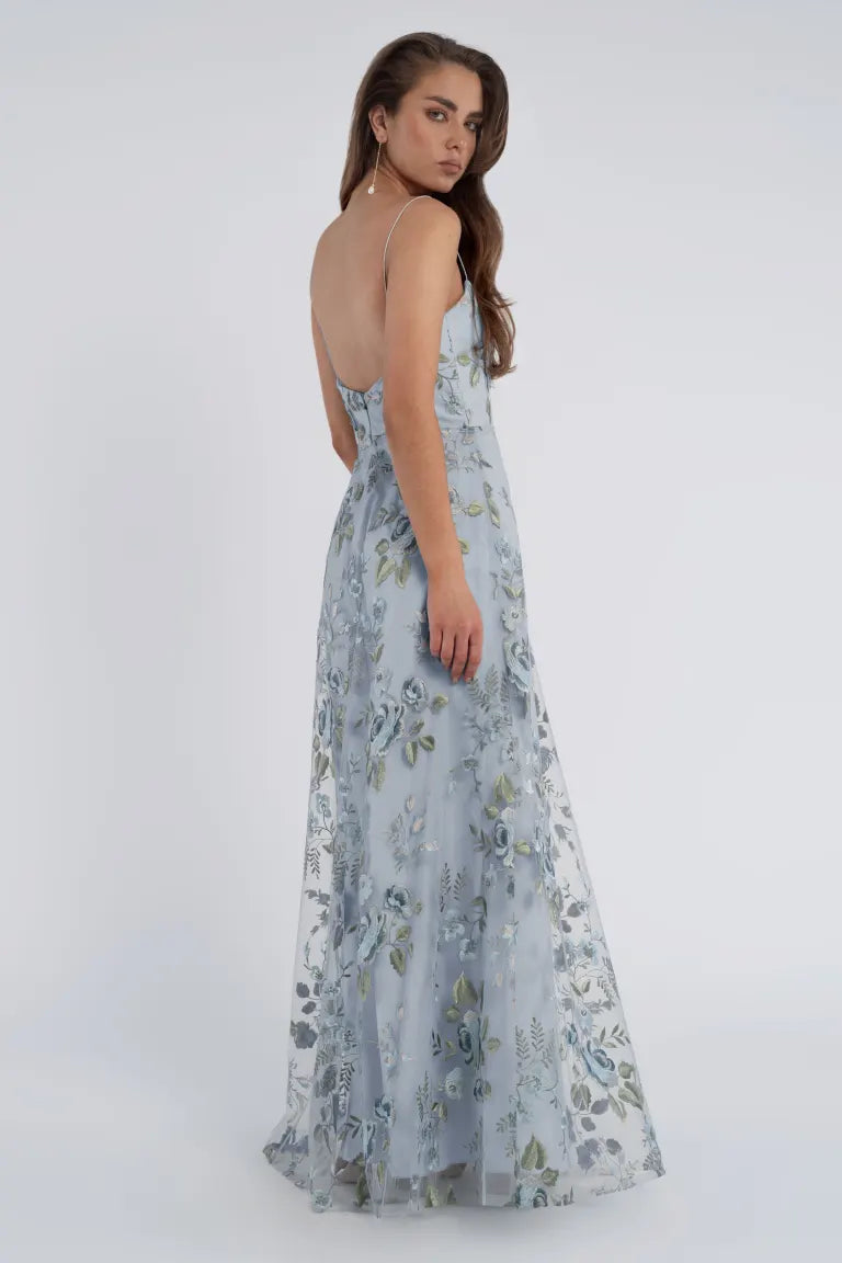 Woman in an enchanted blue floral tulle Drew - Jenny Yoo Bridedmaid Dress looking over her shoulder from Bergamot Bridal.