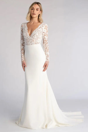 A woman modeling an elegant Julian - Jenny Yoo wedding dress from Bergamot Bridal with lace sleeves and a deep v-neckline, adorned with embroidered florals throughout its fit and flare silhouette.