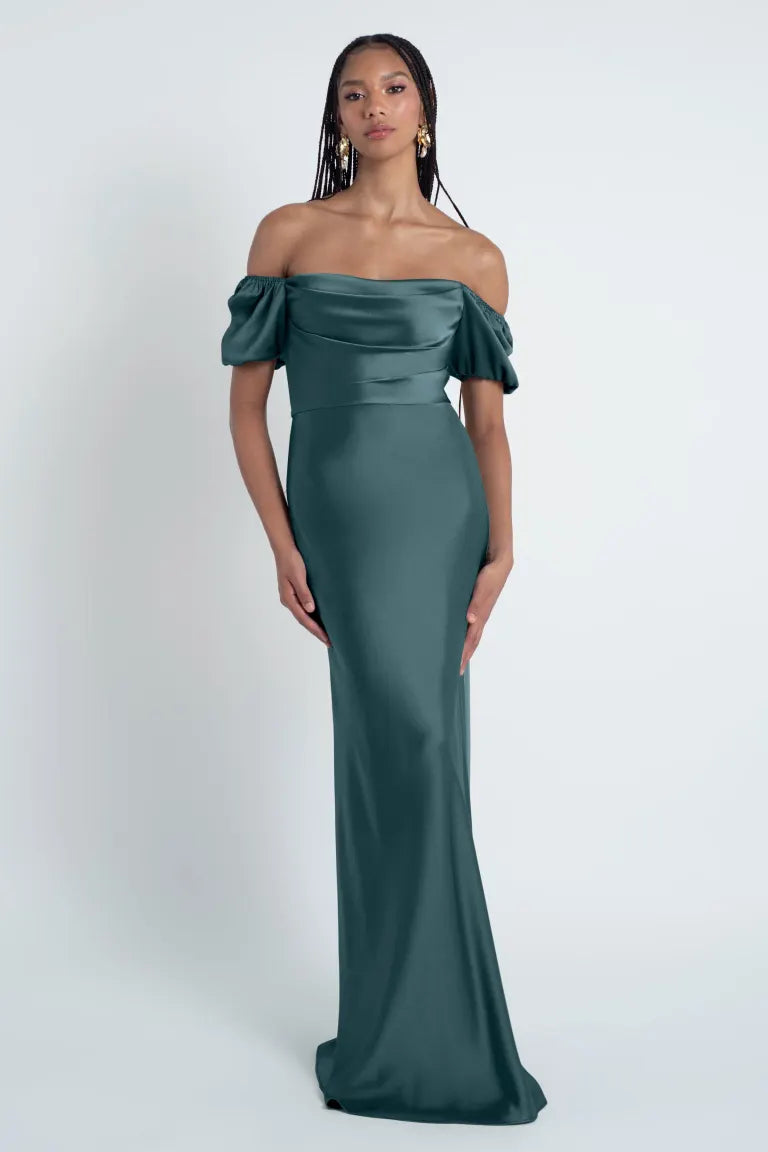 A woman wearing an elegant off-the-shoulder teal Jenny Yoo Bridesmaid Dress with puff sleeves from Bergamot Bridal.