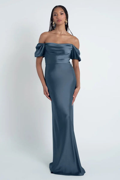 A woman in an elegant off-the-shoulder Jenny Yoo Bridesmaid Dress with puff sleeves stands against a neutral background.