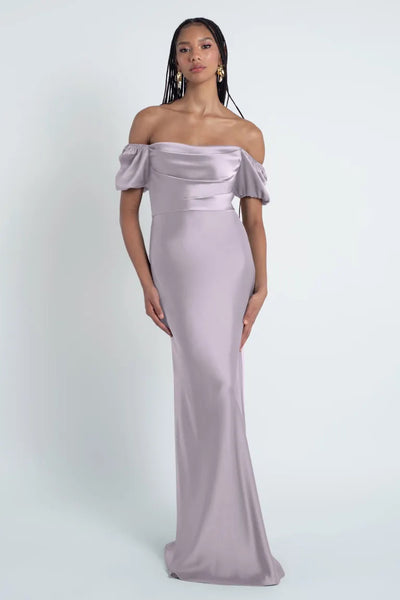 Woman in an elegant off-the-shoulder mauve Eliana - Jenny Yoo Bridesmaid Dress made of satin fabric from Bergamot Bridal.