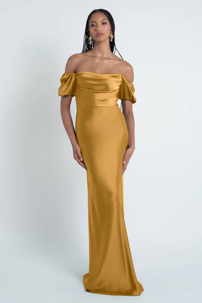 Woman in an elegant off-shoulder golden Jenny Yoo Bridesmaid Dress with a bias-cut skirt from Bergamot Bridal.