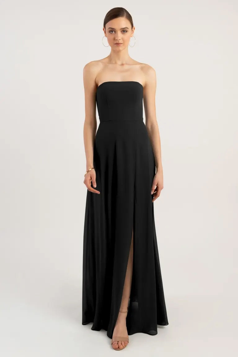A woman wearing a strapless Essie bridesmaid dress by Jenny Yoo with an A-line skirt and a thigh-high slit from Bergamot Bridal.