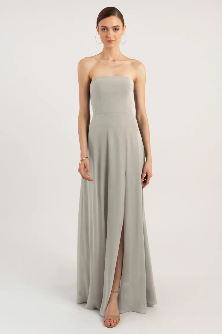 Woman posing in a strapless gray Essie Bridesmaid Dress by Jenny Yoo with a high slit from Bergamot Bridal.