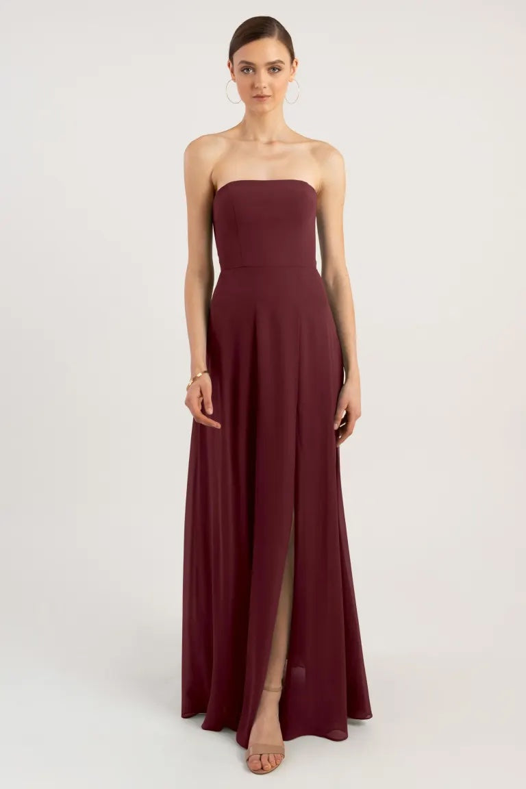 Woman in an elegant maroon Essie - Bridesmaid Dress by Jenny Yoo chiffon with a strapless neckline and a side slit.
