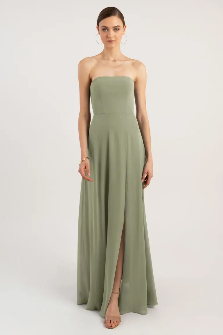 Woman in a sleek, strapless green Essie bridesmaid dress by Jenny Yoo with a slit from Bergamot Bridal.