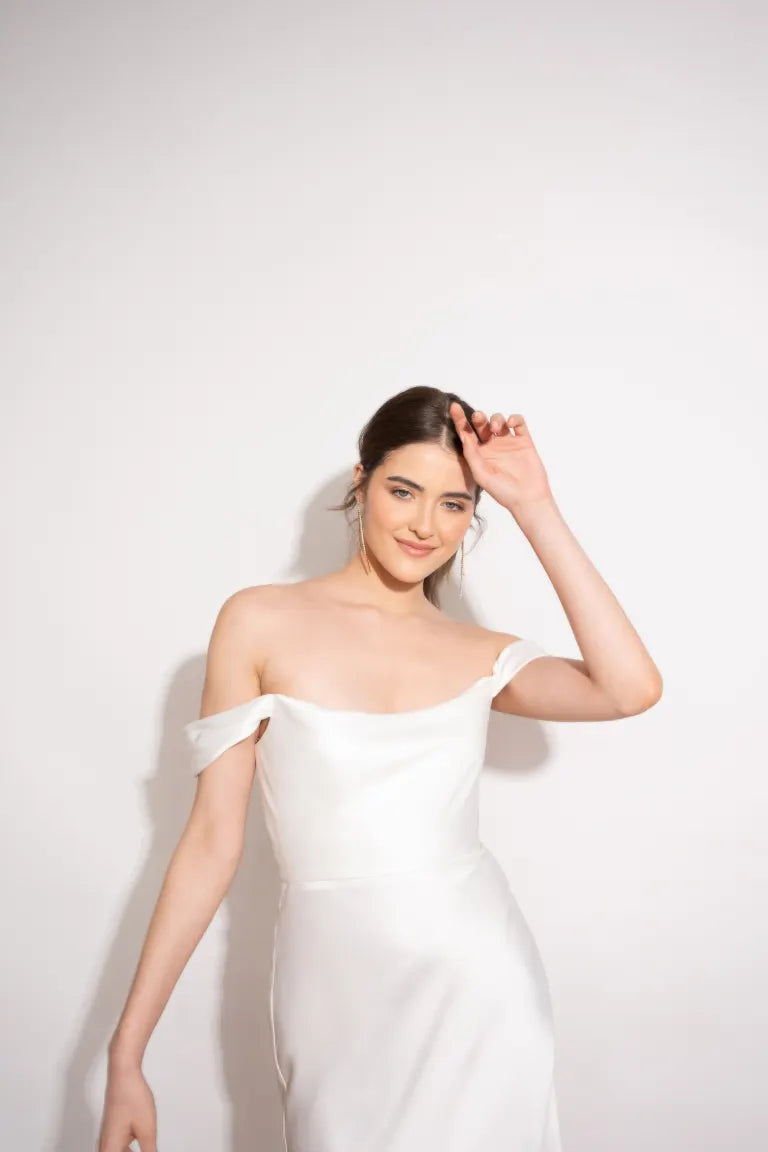 A woman is stunningly posing in a mesmerizing Evelyn - Jenny Yoo Little White Dress by Bergamot Bridal.
