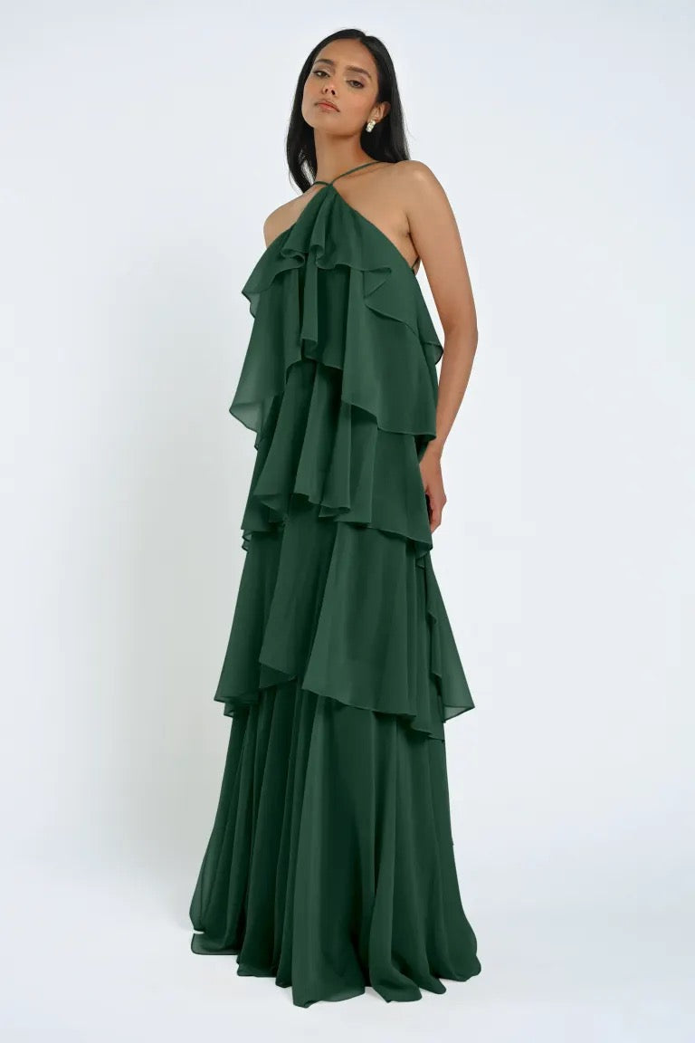 A woman wearing the ethereal sleeveless Farley Bridesmaid Dress by Jenny Yoo in a refreshing green hue, stands against a plain white background, exuding an effortless elegance.