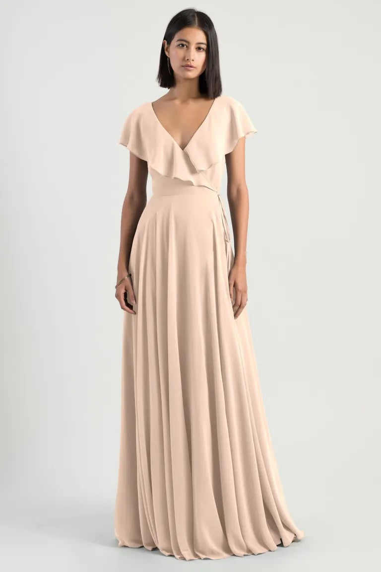 Woman in an elegant Faye - Bridesmaid Dress by Jenny Yoo chiffon wrap dress with a v-neckline and ruffle flutter sleeve from Bergamot Bridal.