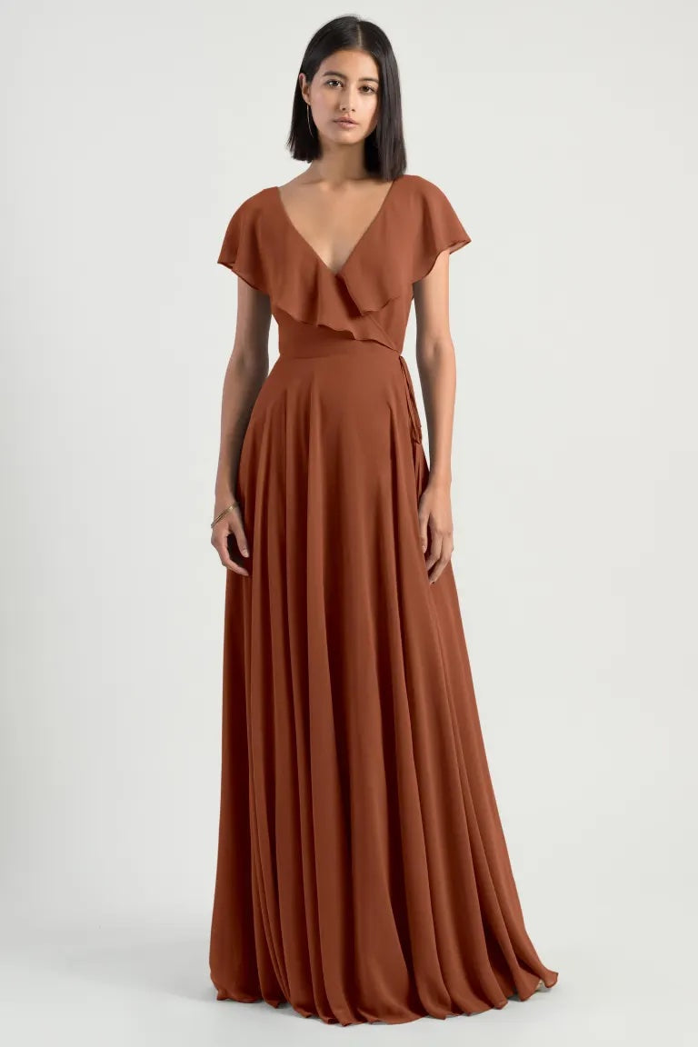 A woman in a romantic Faye - Bridesmaid Dress by Jenny Yoo chiffon wrap dress with flutter sleeves and a v-neckline from Bergamot Bridal.