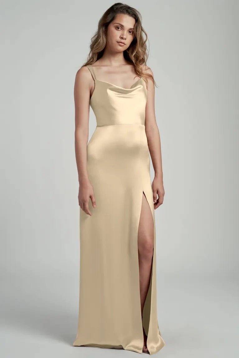 Woman posing in an elegant beige satin bridesmaid dress with a cowl neckline, Gina - Bridesmaid Dress by Jenny Yoo from Bergamot Bridal.