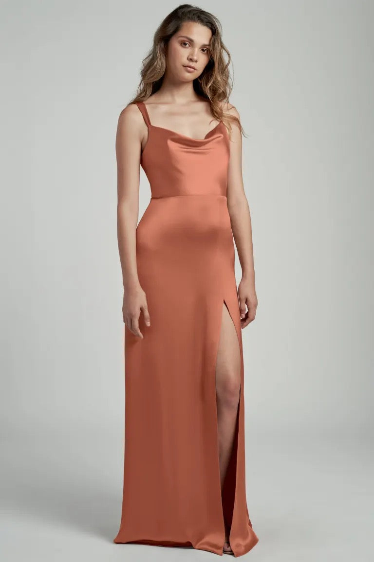Woman in an elegant Gina - Bridesmaid Dress by Jenny Yoo in terracotta satin with a cowl neckline from Bergamot Bridal.