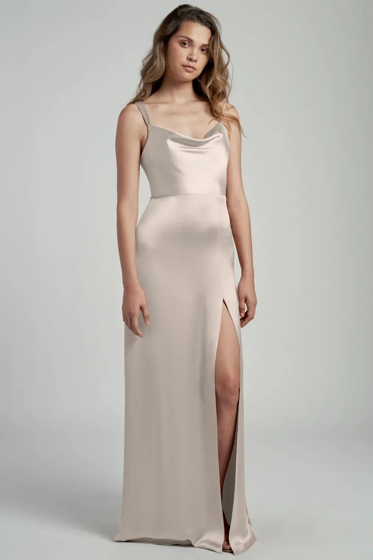 Woman in a sleek, satin bridesmaid dress with a cowl neckline and a thigh-high slit, the Gina Bridesmaid Dress by Jenny Yoo from Bergamot Bridal.